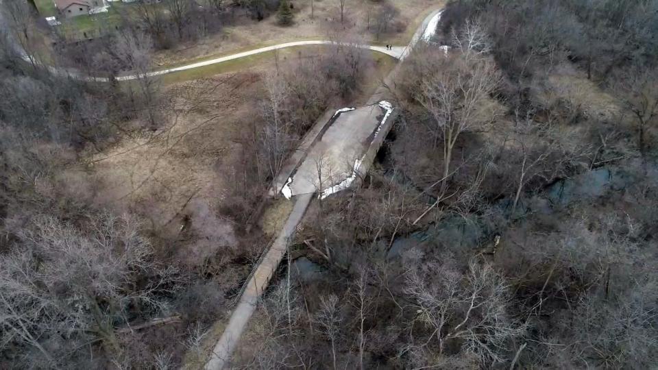 An aerial view looking to the east shows two bridges along the Oak Leaf Trail near the Root River in Greenfield. The large bridge near the center of the image was built around 1970 and designed for a road project that was later abandoned. A smaller bridge, constructed when the trail was put in, crosses the Root River and can be seen to the west of the large bridge.