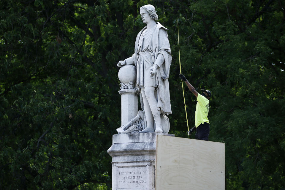 FILE - In this June 16, 2020 file photo, a city worker measures the statue of Christopher Columbus at Marconi Plaza in Philadelphia. The statue remains hidden by a plywood box while its fate is decided in the courts, but the box has now been painted with the colors of the Italian flag. City officials told the news station KYW that they painted the box covering the 146-year-old statue in south Philadelphia's Marconi Plaza with green, white and red stripes at the request of Councilmember Mark Squilla, who represents the district. (AP Photo/Matt Slocum, File)