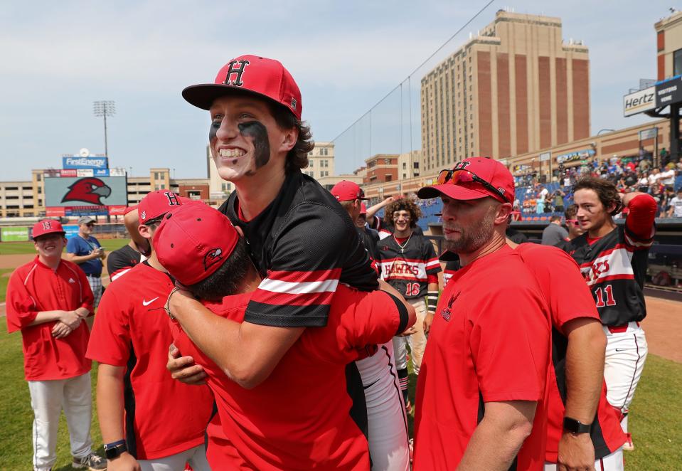 Hiland pitcher Isaak Yoder is lifted up by a member of the Hawks coaching staff after beating Russia, 14-4, to win the OHSAA Division IV state championship baseball game at Canal Park, Saturday, June 10, 2023, in Akron, Ohio.