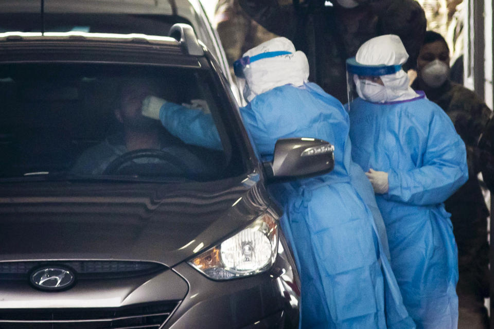 FILE - In this March 24, 2020, file photo, the Illinois National Guard operates a COVID-19 drive-thru test site for medical personnel and first responders in Chicago. The use of National Guard units around the country to help with the response to the coronavirus pandemic is prompting rumors of a national lockdown or even martial law. Guard units are now helping to transport medical supplies, distribute food and even help direct traffic at drive-thru testing sites. (Ashlee Rezin Garcia/Chicago Sun-Times via AP, File)