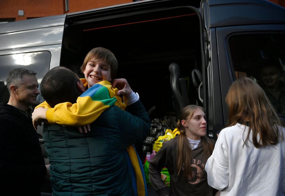 A Ukrainian man meets his children Nikita, Yana, and Dayana after they were brought back from Russian captivity to Kyiv on March 22, 2023. (Photo by Sergei Chuzavkov/AFP via Getty Images)