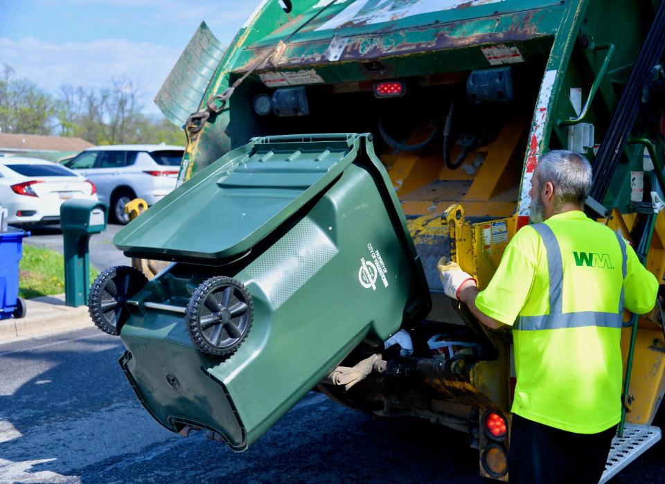 One of the City of Hagerstown's new residential 95-gallon trash totes is dumped into a Waste Management garbage truck on Monday morning along Woodpoint Avenue. While the current trucks allow for an employee to roll the can over so it can be mechanically dumped into the truck, the company is expecting to switch this summer to newer trucks that automatically grab a can and lift it for emptying.