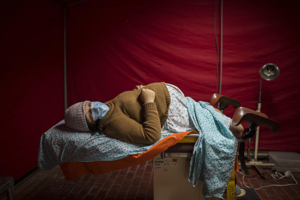 En esta imagen, tomada el 29 de julio de 2020, Olinda Tafur, de 20 años, espera sobre una camilla a ser atendida por el obstetra Osvaldo Sierra, dentro de una tienda de campaña instalada en la zona de urgencias del Instituto Nacional Materno Perinatal para recibir a las mujeres de parto que están contagiadas de COVID-19 en Lima, Perú. Tafur se enteró de que había dado positivo al coronavirus al llegar con dolores de parto a urgencias para dar a luz a su primer hijo. (AP Foto/Rodrigo Abd)