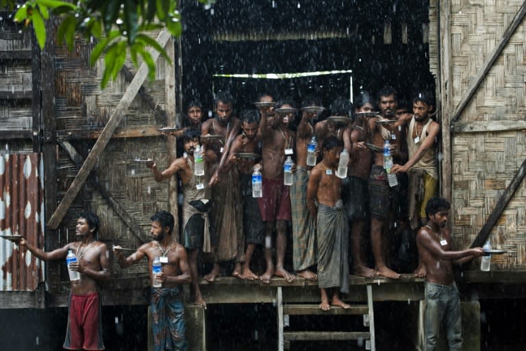 Migrants rescued at sea collect rain water at a temporary shelter near the Kanyin Chaung jetty in Rakhine state in June 2015