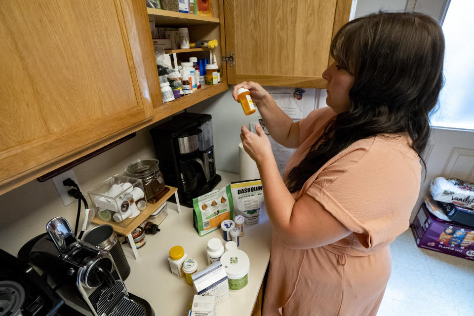 Richelle Dietz looks at their medications at her home on Monday, April 22, 2024, in Honolulu, Hawaii. The Dietz family has acquired a dozen more medications since their water was tainted by a jet fuel leak in 2021. (AP Photo/Mengshin Lin)