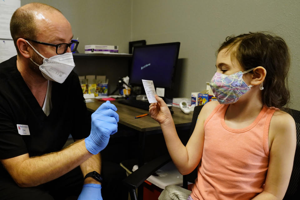 McKenna Brown, 10, is given her vaccination card from Pharmacist Clint Hopkins as she was given a Pfizer COVID-19 vaccine at Pucci's Pharmacy in Sacramento, Calif., Tuesday, Jan. 25, 2022. California is showing signs that it may have turned the corner on the latest omicron wave of the coronavirus pandemic, with cases falling and hospitalizations short of the overwhelming deluge that officials had predicted just weeks ago. (AP Photo/Rich Pedroncelli)