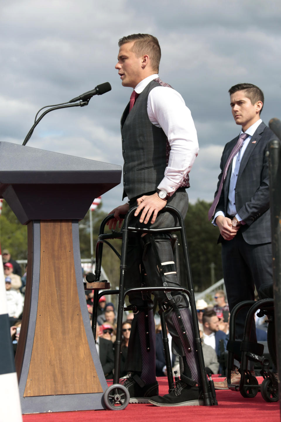 U.S. Rep. Madison Cawthorn, R-N.C., gets up from his wheelchair to speak before former President Donald Trump takes the stage at a rally, Saturday, April 9, 2022, in Selma, N.C. (AP Photo/Chris Seward)