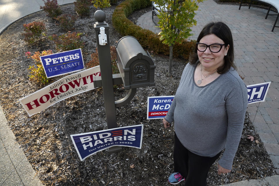 Lori Goldman poses for a portrait next to campaign signs outside her home in Bloomfield Village, Mich., Friday, Oct. 9, 2020. For most of her life, until 2016, Goldman had been politically apathetic. Had you offered her $1 million, she says, she could not have described the branches of government in any depth. She voted, sometimes. (AP Photo/Paul Sancya)