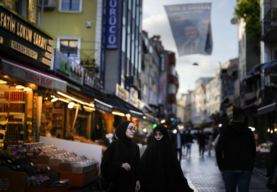 Women walk in an outdoor market in Fatih district of Istanbul, Turkey, Tuesday, May 23, 2023. Two opposing visions for Turkey’s future are on the ballot when voters return to the polls Sunday for a runoff presidential election, which will decide between an increasingly authoritarian incumbent President Recep Tayyip Erdogan and challenger Kemal Kilicdaroglu, who has pledged to restore democracy. (AP Photo/Khalil Hamra)