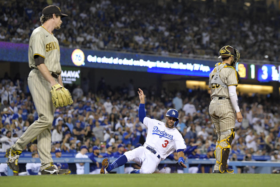 Los Angeles Dodgers' Chris Taylor, center, scores on a sacrifice fly by Cody Bellinger as San Diego Padres relief pitcher Tim Hill, left, and catcher Austin Nola watch during the eighth inning of a baseball game Friday, July 1, 2022, in Los Angeles. (AP Photo/Mark J. Terrill)