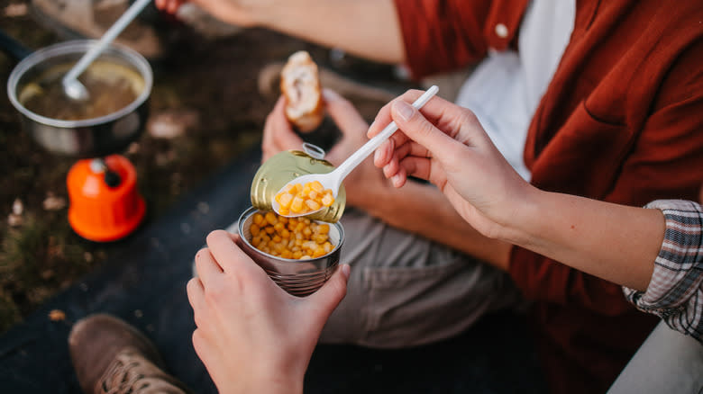 eating canned corn by campfire