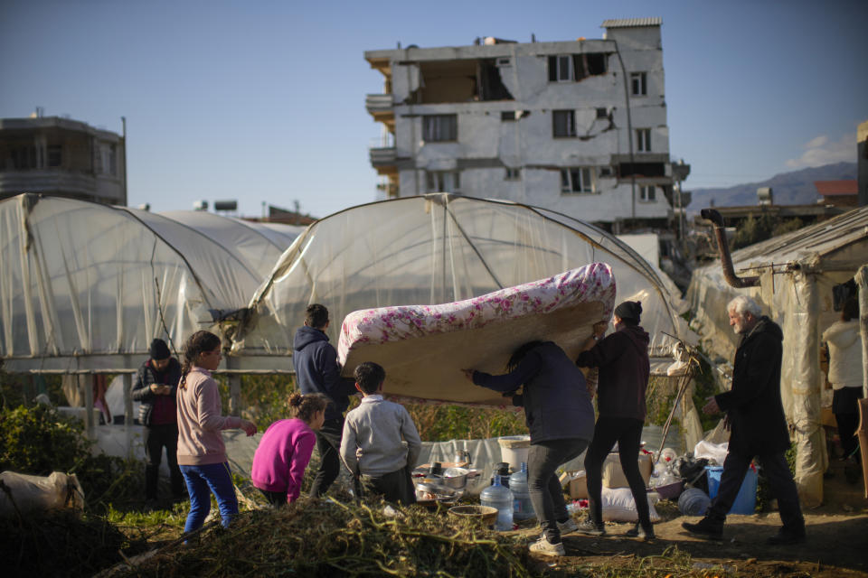 FILE - Local residents bring a mattress to a greenhouse where they shelter after the earthquake in Samandag, southern Turkey, on Feb. 16, 2023. Hundreds of thousands of people are seeking shelter after the Feb. 6 earthquake in southern Turkey left homes unlivable. Many survivors have been unable to find tents or containers dispatched to the region by the government and aid agencies, Instead they have sought refuge in any structure that can protect them from the winter conditions, including greenhouses, rail carriages and factories. (AP Photo/Francisco Seco)