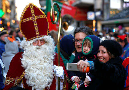 Saint Nicholas poses with a family during a traditional parade in central Brussels, Belgium December 3, 2016. REUTERS/Yves Herman