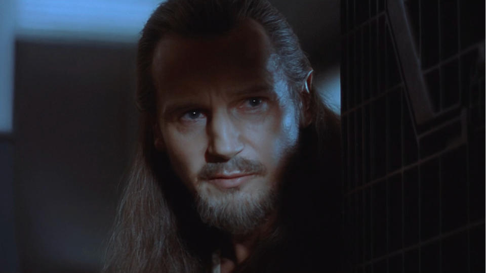 Liam Neeson hiding in the shadows with a clever look in Star Wars: The Phantom Menace.