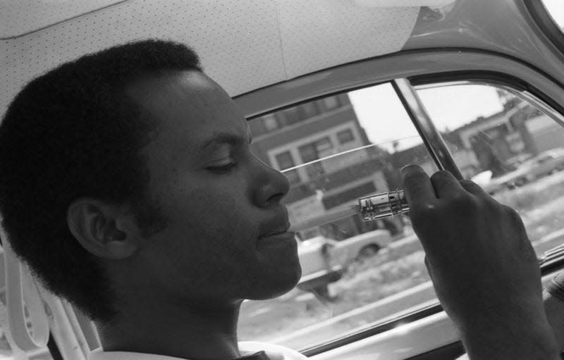 View of photographer Robert Abbott Sengstacke, using a car lighter to light a cigarette while driving, Chicago, Illinois, mid to late 1960s (between 1966 and 1968). - Photo: Robert Abbott Sengstacke (Getty Images)