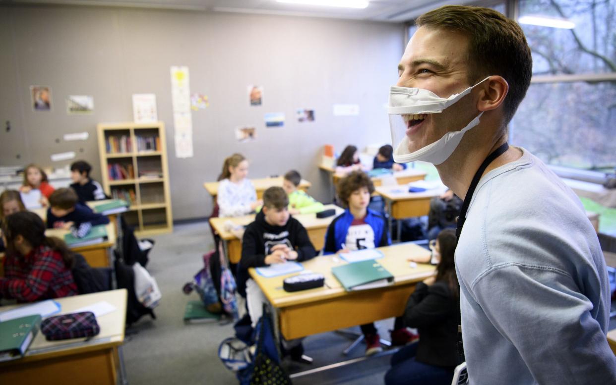 eacher Matthieu Macchi wears a transparent protective face mask during class to help his student who is hard of hearing to understand and communicate easier at a primary school, in Lausanne, Switzerland -  Shutterstock