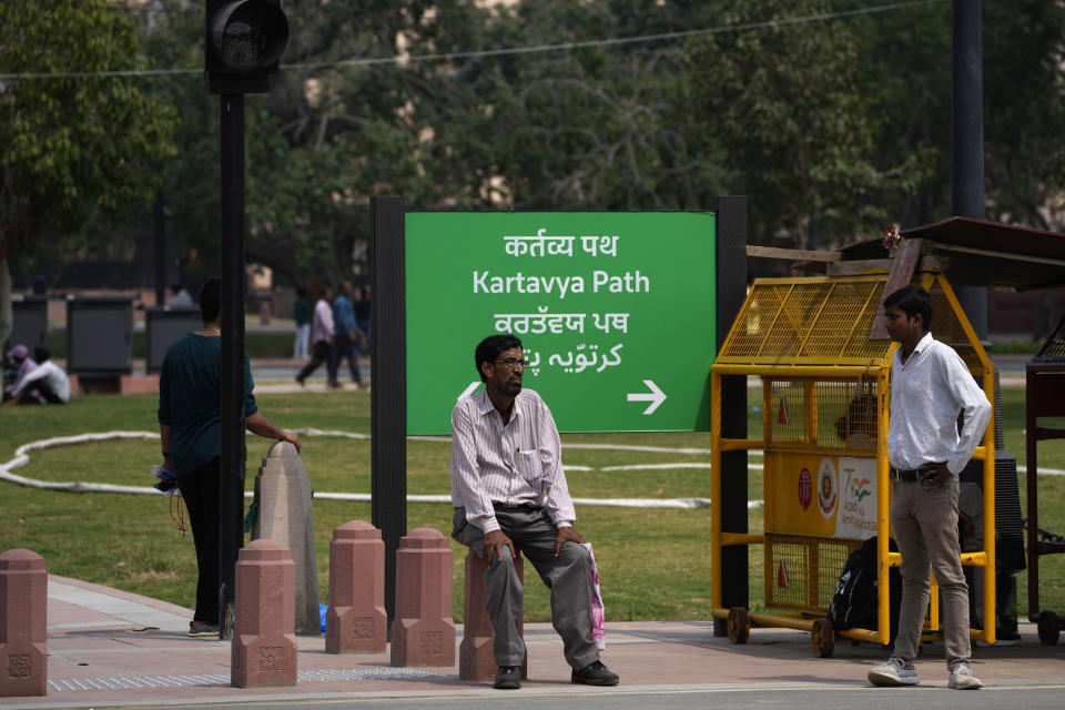A man rests on a newly constructed pillar in front of a road signage which is changed from Rajpath to Kartavya Path, in New Delhi, Sunday, Sept. 11, 2022. On Thursday, Sept. 8, 2022, India’s Prime Minister Narendra Modi urged the country to shed its colonial ties in a ceremony to rename Rajpath, a boulevard that was once called Kingsway after King George V, Modi called it a "symbol of slavery" under the British Raj. (AP Photo/Manish Swarup)