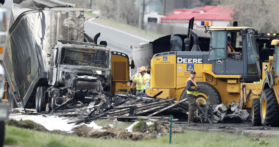 FILE--In this Friday, April 26, 2019, file photograph, workers clear debris from the eastbound lanes of Interstate 70 in Lakewood, Colo., after four motorists died in a fiery pileup involving 28 vehicles at the start of the evening rush hour traffic Thursday, April 25. A semi-truck hauling lumber plowed into the vehicles as they were caught in a traffic jam on Denver's west side. The driver of the truck accused of causing the pileup pleaded not guilty to vehicular homicide and other charges in Jefferson County, Colo., court Thursday, Nov. 21, 2019. (AP Photo/David Zalubowski, File)