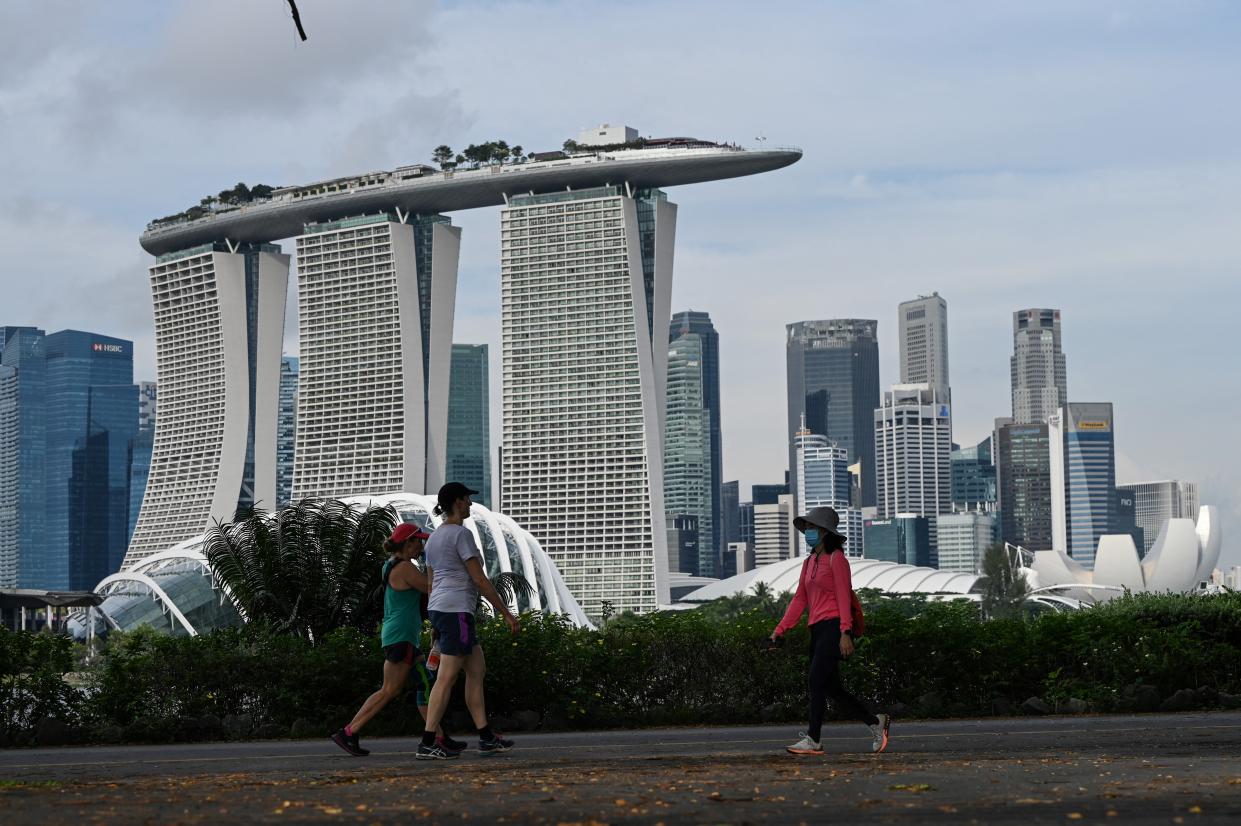 People walk along Marina Bay East Park near the financial business district in Singapore on October 20, 2021. / AFP / Roslan RAHMAN