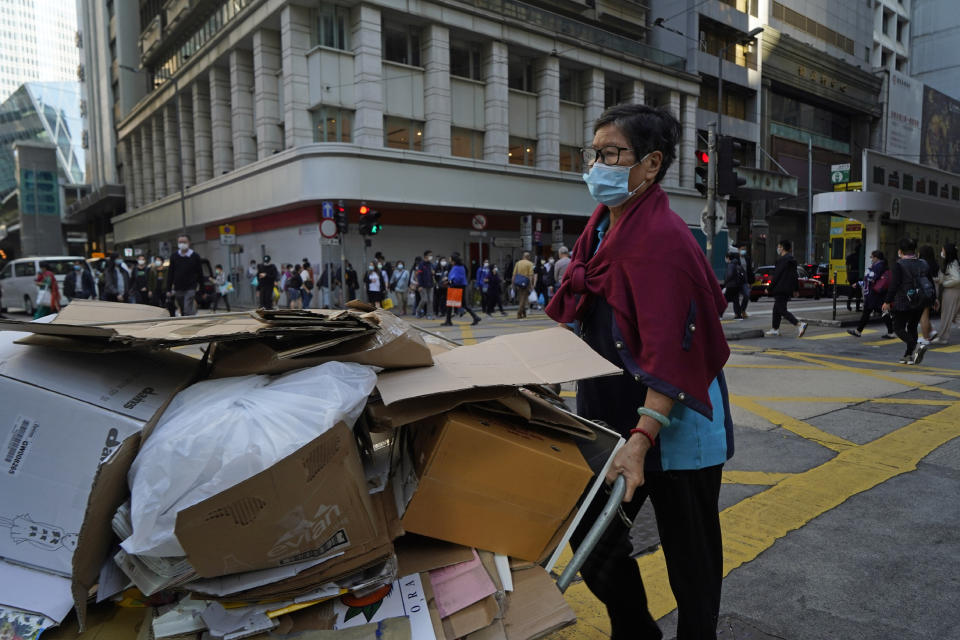 A woman wearing a mask to help protect herself from the coronavirus, pushes a trolley along a street in Hong Kong, Monday, Nov. 30, 2020. (AP Photo/Kin Cheung)