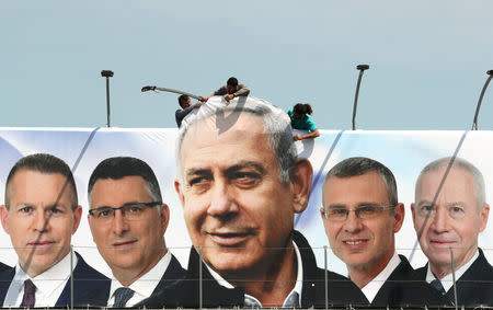 Labourers work on hanging up a Likud election campaign banner depicting Israeli Prime Minister Benjamin Netanyahu with his party candidates, in Jerusalem March 28, 2019. REUTERS/Ammar Awad/Files