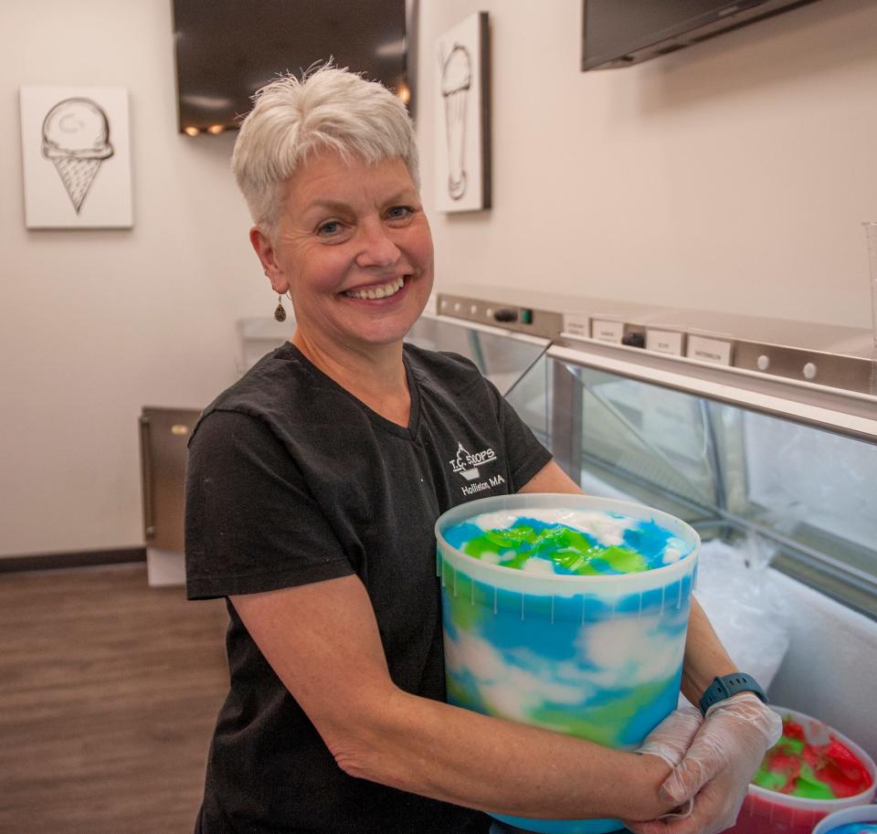T.C. Scoops owner Tina Chemini holds a tub of tie-dye Italian ice — a mix of green apple, lemon and blue raspberry — inside her new Holliston store, April 19, 2023.