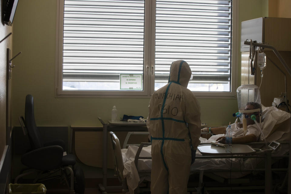 FILE - In this April 8, 2020 file photo, deputy head of the intensive care unit Flavio Tangian talks with a COVID-19 patient under treatment in the intensive care unit ICU at the Circolo hospital, in Varese, Italy. Italy is poised to reclaim the dishonor of reporting the most coronavirus deaths in Europe, as the second surge ravages the country’s disproportionately old population and exposes how public health shortfalls and delayed restrictions compounded a lack of preparedness going into the pandemic. (AP Photo/Luca Bruno, file)