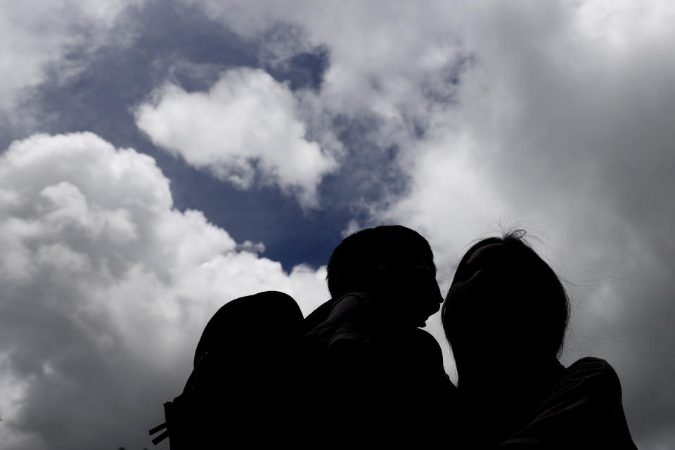 Pamela Lam and her son are silhouetted in Hong Kong, Friday, July 3, 2020. Lam's 6-year-old son fell in love with the Hong Kong protest anthem, "Glory to Hong Kong," the first time he heard it and sings it quite often. Thanks to a sweeping new national security law, though, singing it in public is now risky. Lam agreed to be photographed only if her face was not shown, fearing possible retribution from authorities. (AP Photo/Kin Cheung)