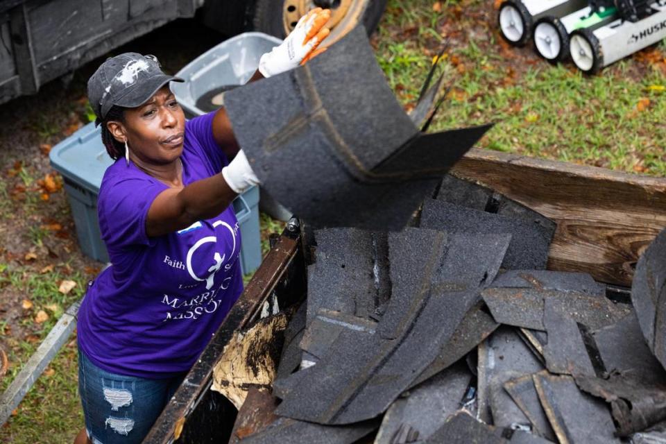 Shawna Hayes disposes of old shingles while volunteering with Home Works of America on Saturday, May 20, 2023.