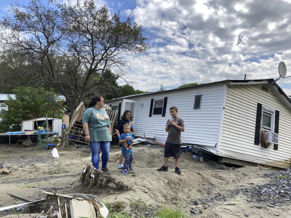 Sara Morris, left, and her children stand outside their flood-ravaged mobile home in Berlin, Vt., on Tuesday, Aug. 29, 2023. With Vermont’s already tight housing market and cold weather fast approaching, some flood victims who lost homes don’t yet know where they’ll live. (AP Photo/Lisa Rathke)