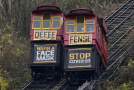 The cars on the Duquesne Incline pass each other carrying signs encouraging face mask wearing on Sunday, Nov. 22, 2020 in downtown Pittsburgh. (AP Photo/Gene J. Puskar)