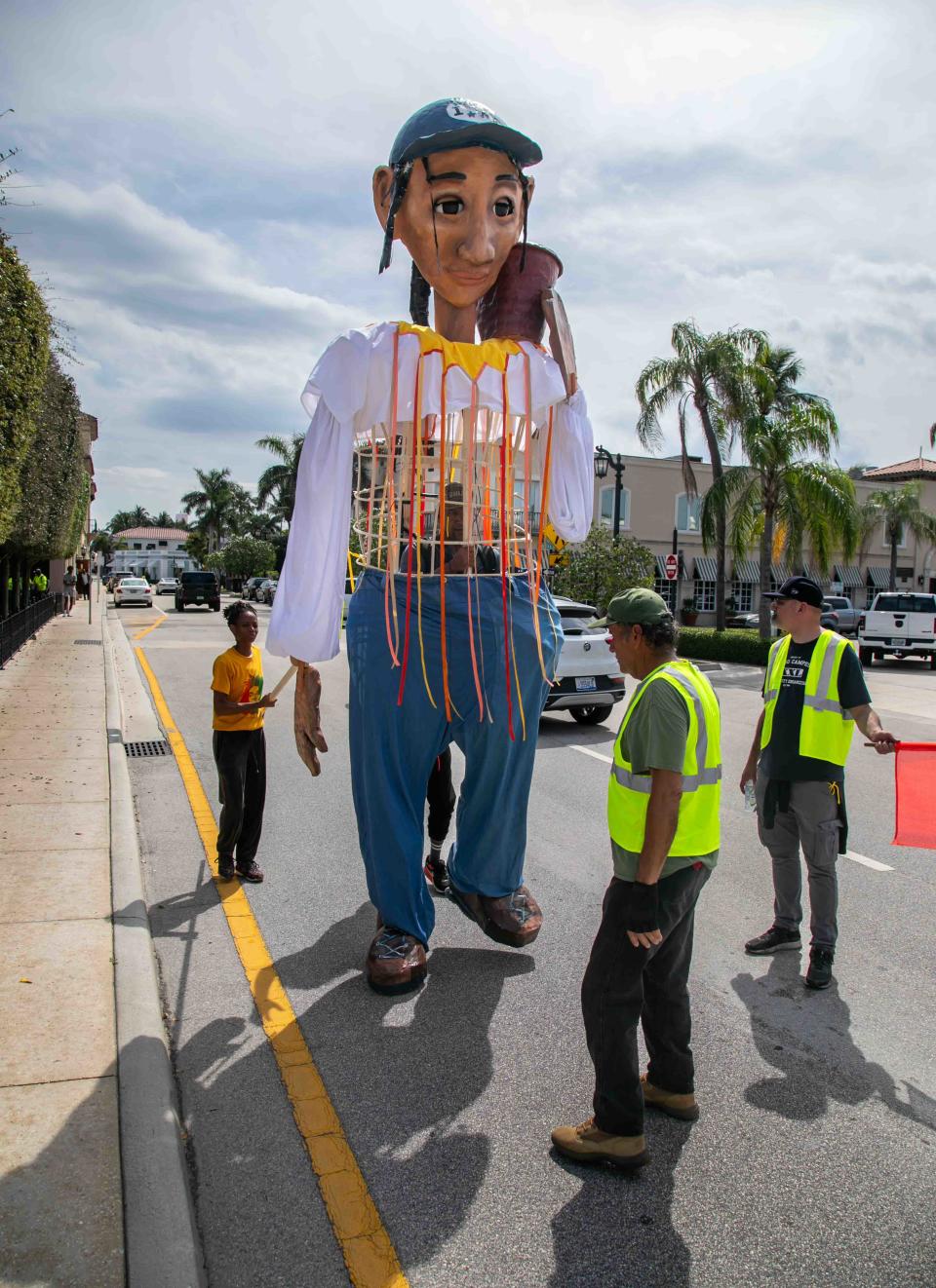 A 16-foot puppet named Esperanza is taken north along South County Road on Friday.