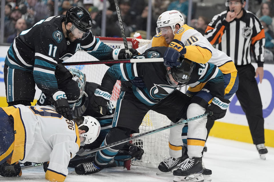 Nashville Predators' Colton Sissons (10) San Jose Sharks' Jan Rutta (84) and Luke Kunin (11) vie for the puck in front of the net during the second period of an NHL hockey game Saturday, Feb. 24, 2024, in San Jose, Calif. (AP Photo/Tony Avelar)