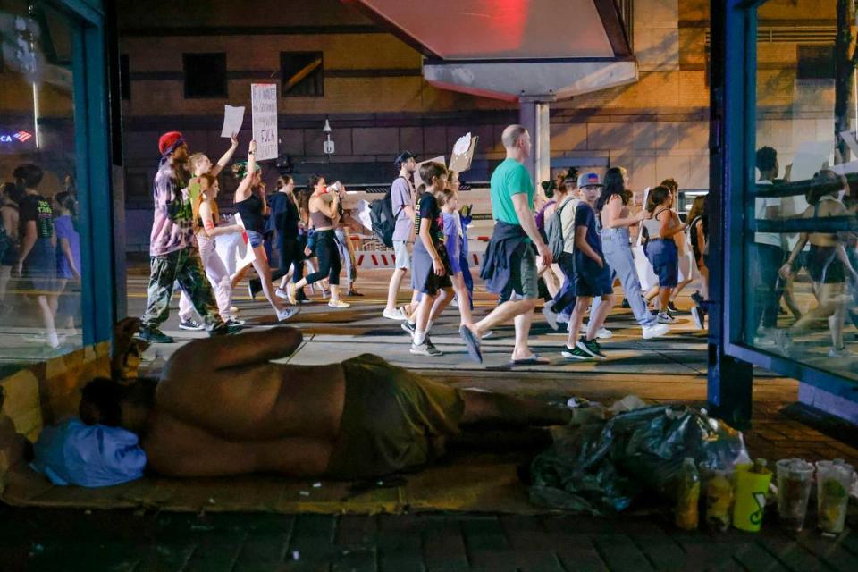 Abortion rights activists march along East Trade Street near a homeless person in Charlotte, N.C., Sunday, June 26, 2022. The demonstration was in response to last week’s decision from the U.S. Supreme Court to overturn Roe v. Wade.