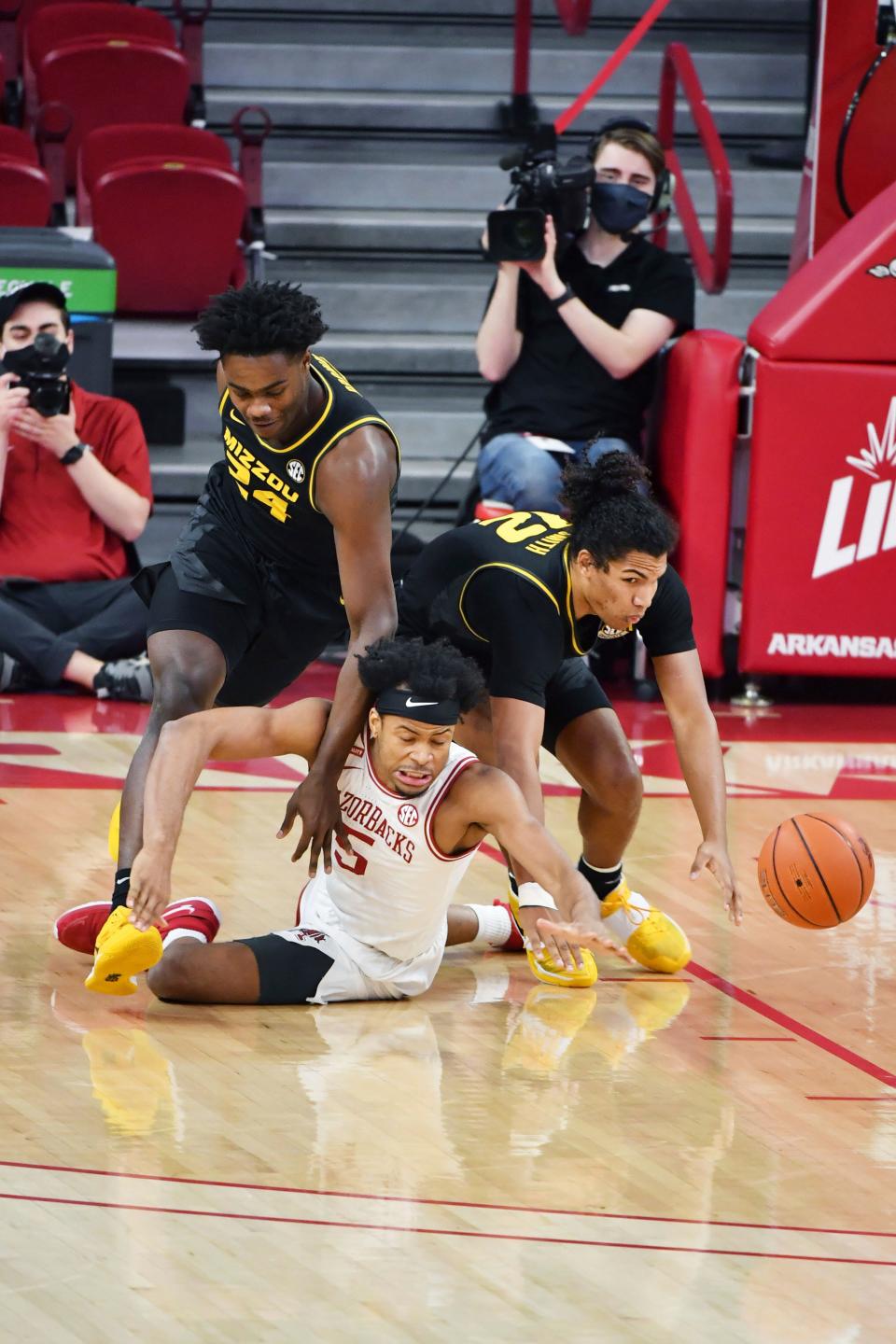 Arkansas forward Moses Moody (5) and Missouri's Kobe Brown (24) and Dru Smith (12) fight for a loose ball during the first half of an NCAA college basketball game in Fayetteville, Ark. Saturday, Jan. 2, 2021. (AP Photo/Michael Woods)