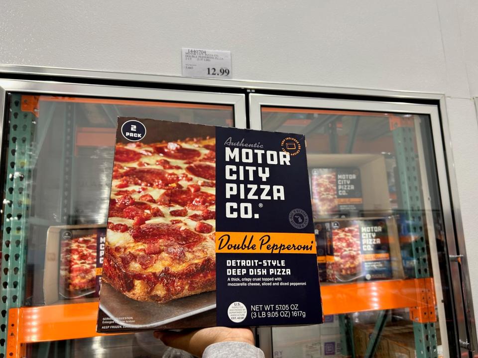 hand holding up a box of motor city pizza co frozen pizze in the aisles at Costco