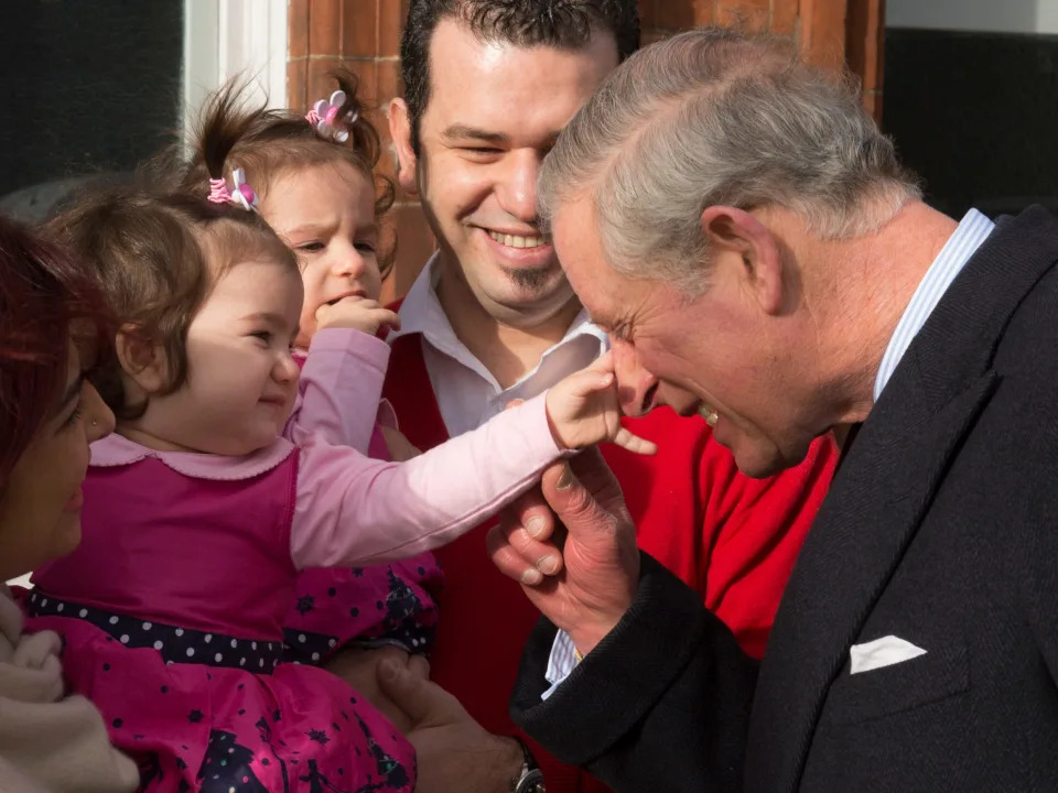 A baby girl grabs Prince Charles' nose