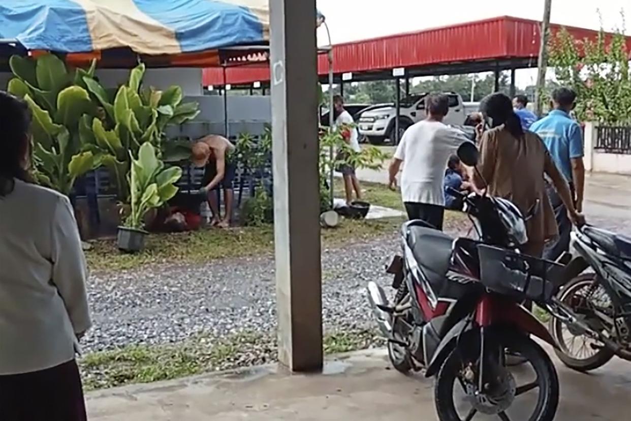 In this image taken from video, a distraught woman is comforted outside the site of an attack at a daycare center, Thursday, Oct. 6, 2022, in the town of Nongbua Lamphu, northeastern Thailand.