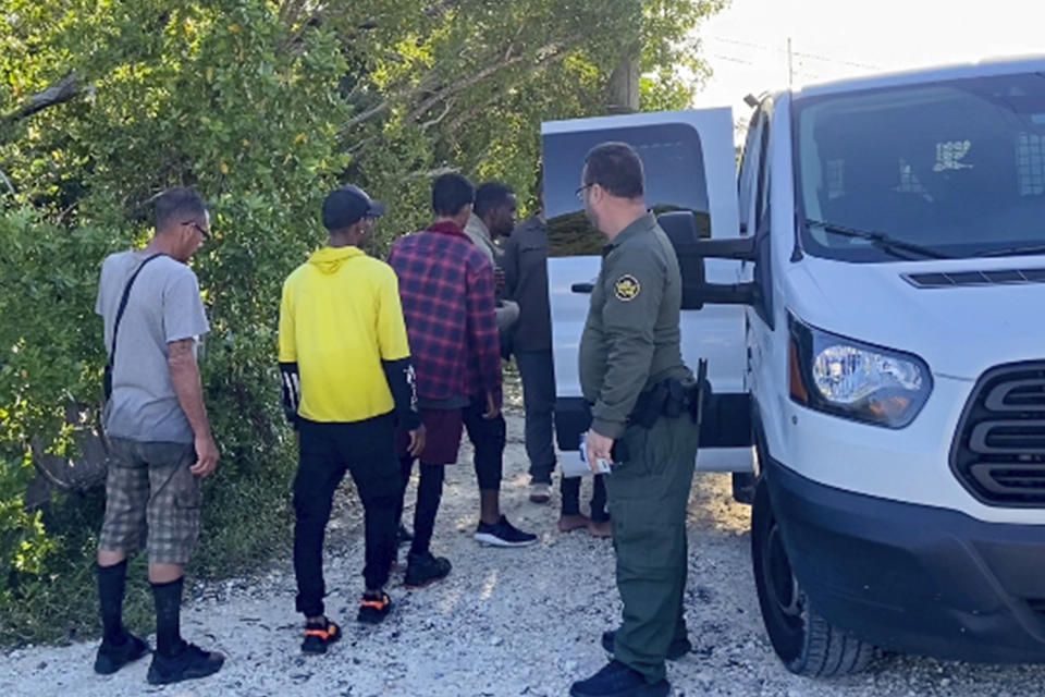 CORRECTS YEAR TO 2023 NOT 2022 - A U.S. Border Patrol agent attends to migrants by a van parked on Garden Cove Road in Key Largo, Fla., Tuesday, Jan. 3, 2023. (David Goodhue/Miami Herald via AP)