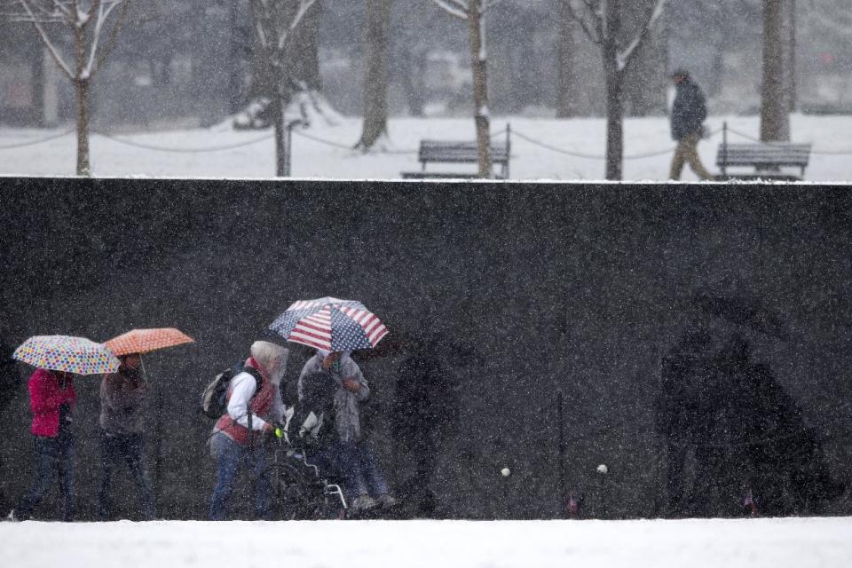 Visitors visit Vietnams Veterans Memorial during a snow storm in Washington, Tuesday, March 25, 2014. The calendar may say it's spring, but the mid-Atlantic region is seeing snow again. The National Weather Service has issued a winter weather advisories for much of the region Tuesday. The advisories warn that periods of snow could make travel difficult, with slippery roads and reduced visibility. (AP Photo/ Evan Vucci)