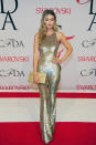 Gigi Hadid wearing a glittery golden jumpsuit with equally gilded accessories, nails and waves.