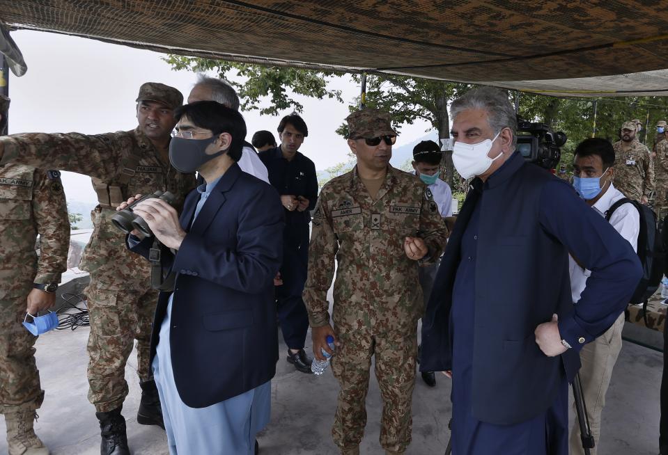 A senior army officer, center, briefs to Pakistani Foreign Minister Shah Mahmood Qureshi, 1st right, and Moeed Yusuf, the National Security Advisor to the Prime Minister of Pakistan, 2nd left, during their visit to forward area post along a highly militarized frontier in the disputed region of Kashmir, in Chiri Kot sector, Pakistan, Monday, Aug. 3, 2020. The region's top Pakistani military commander briefed ministers about Indian cease-fire violations in Kashmir, which is split between Pakistan and India and claimed by both in its entirety. (AP Photo/Anjum Naveed)