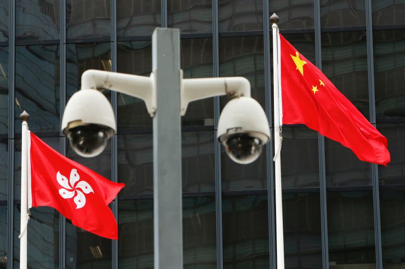 FILE PHOTO: Hong Kong and Chinese national flags are flown behind a pair of surveillance cameras outside the Central Government Offices in Hong Kong