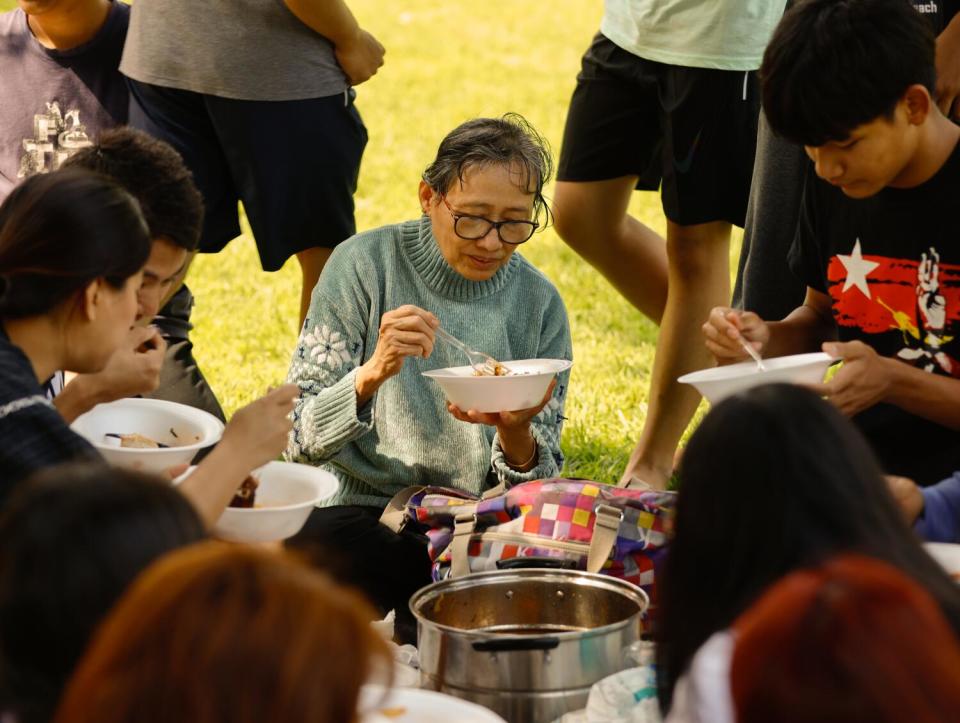 A group of people on a picnic blanket, eating