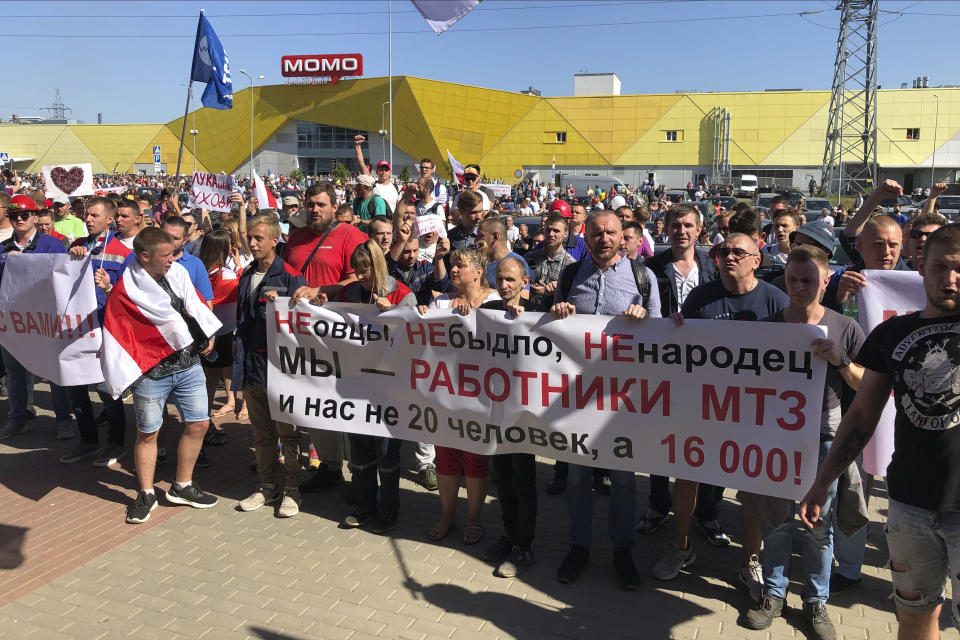 Workers hold a banner reading "we are not cattle, we are not sheep, we are workers of the Minsk Tractor Works Plant, we are not 20 people, we are 16,000" in front of the Minsk Wheel Tractor Plant where Belarusian President Alexander Lukashenko addresses employees in Minsk, Belarus, Monday, Aug. 17, 2020. The top opposition candidate in Belarus' presidential vote who left the country last week announced Monday she was ready to "act as a national leader" to help Belarus transition to a rerun of an election that extended the 26-year rule of authoritarian President Alexander Lukashenko and sparked unprecedented mass protests. (AP Photo/Sergei Grits)