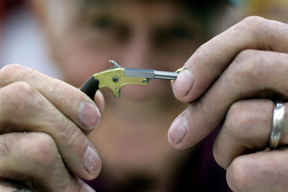 FILE - In this, May 21, 2016, file photo, Bob McGinnis, of Cross Plains, Wis., holds a miniature gun he has made at a display of the Miniature Arms Society at the National Rifle Association convention in Louisville, Ky. The convention, that started in 1871 as a group devoted to hunting, shooting sports and gun safety, has evolved into one of the most powerful forces in American politics. (AP Photo/Mark Humphrey, File)