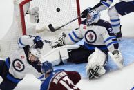 Colorado Avalanche right wing Valeri Nichushkin, foreground shoots the puck past Winnipeg Jets defenseman Neal Pionk, left, and goaltender Connor Hellebuyck for a goal during the third period of Game 3 of an NHL hockey Stanley Cup first-round playoff series Friday, April 26, 2024, in Denver. (AP Photo/David Zalubowski)
