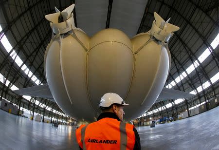 A worker stands under the Airlander 10 hybrid airship during its unveiling in Cardington, Britain March 21, 2016. REUTERS/Darren Staples