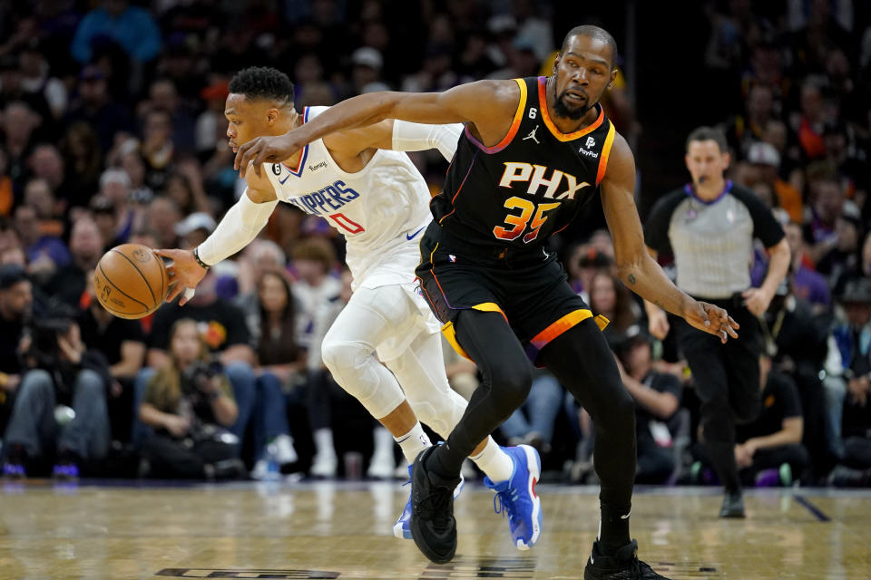 Los Angeles Clippers guard Russell Westbrook (0) moves the ball as Phoenix Suns forward Kevin Durant (35) defends during Game 1 of a first-round NBA basketball playoff series, Sunday, April 16, 2023, in Phoenix. (AP Photo/Matt York)