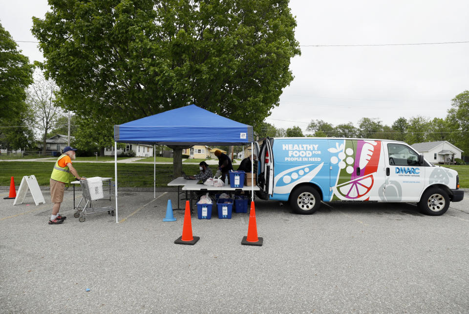 Lewis Claussen, left, stands in line at a Des Moines Area Religious Council Food Pantry stop, Wednesday, May 20, 2020, in Des Moines, Iowa. As food banks have struggled to meet soaring demand from people suddenly out of work because of the coronavirus outbreak, it has been especially troubling to see farmers have to bury produce, dump milk and euthanize hogs. Now some states are spending more money to help pay for food that might otherwise go to waste, the U.S. Agriculture Department is spending $3 billion to help get farm products to food banks, and a senator is seeking $8 billion more to buy farm produce for food banks. (AP Photo/Charlie Neibergall)